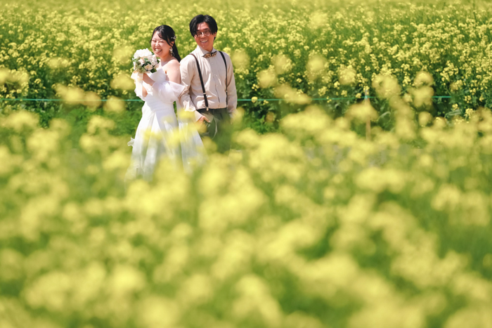 菜の花畑でポーズを決める男女