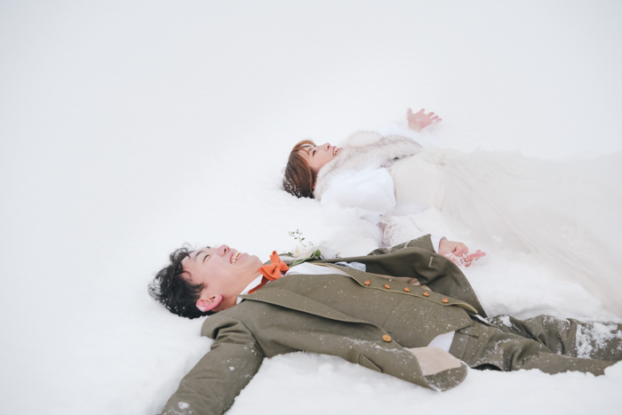 雪の上で寝転ぶ男女